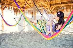 Happy stylish family with cute daughter relaxing in hammock on summer vacation in evening sun light on the beach