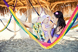 Happy stylish family with cute daughter relaxing in hammock on summer vacation in evening sun light on the beach