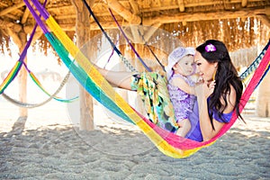 Happy stylish family with cute daughter relaxing in hammock on summer vacation in evening sun light on the beach. hipster couple w