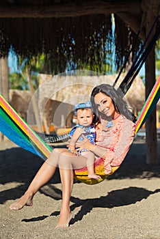 Happy stylish family with cute daughter relaxing in hammock on summer vacation in evening sun light on the beach. hipster couple w