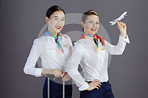 happy stylish female air hostesses isolated on gray background