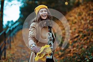 happy stylish female in beige coat and hat enjoying promenade