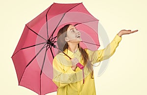 happy stylish girl catch raindrop isolated on white. cheerful teen child hold pink parasol.