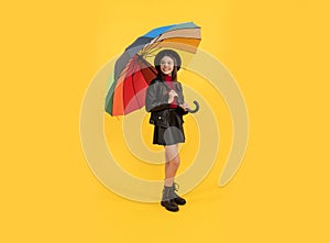 happy stylish girl in leather wear. cheerful teen child hold colorful parasol. kid in hat