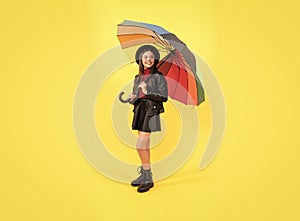 happy stylish girl in leather wear. cheerful teen child hold colorful parasol. kid in hat