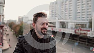 Happy stylish handsome man with a beard drinking takeaway coffee or tea looking to the side.