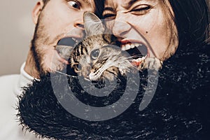 happy stylish hipster family hugging with their cat. man and woman holding kitty and having fun and taking selfie, happy family m