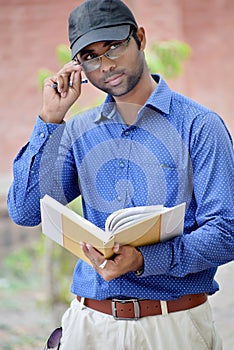 Happy stylish indian young businessman reading book outdoor