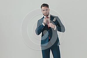 Happy stylish man in suit adjusting red tie and smiling