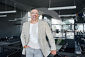 Happy stylish mid aged business man standing in modern office, portrait.