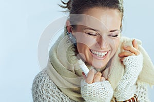 Happy stylish middle age woman with lip balm as winter lip care