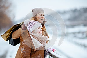 happy stylish mother and child in coat, hat, scarf and mittens