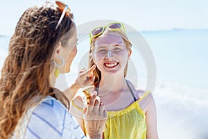 Happy stylish mother and teenage daughter at beach
