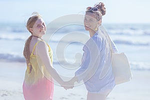 Happy stylish mother and teenage daughter at beach