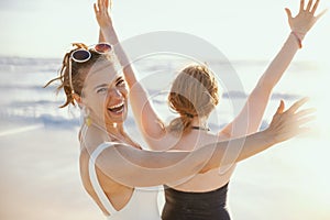 Happy stylish mother and teenage daughter at beach rejoicing