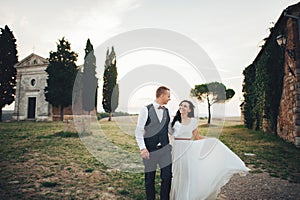 Happy stylish smiling couple walking and kissing in Tuscany, Ita