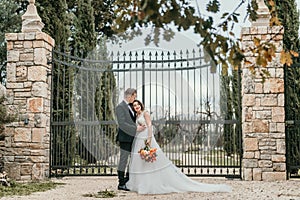 Happy stylish smiling couple walking in Tuscany, Italy on their wedding day. The bride and groom walk down the street by