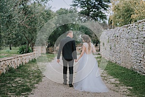 Happy stylish smiling couple walking in Tuscany, Italy on their wedding day. The bride and groom walk down the street by