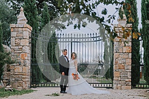 Happy stylish smiling couple walking in Tuscany, Italy on their wedding day. The bride and groom walk down the street by