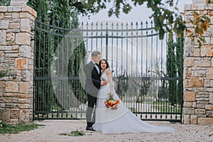 Happy stylish smiling couple walking in Tuscany, Italy on their wedding day. The bride and groom walk down the street by