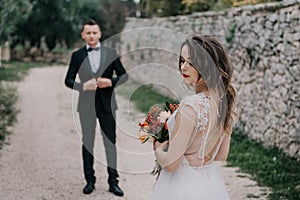 Happy stylish smiling couple walking in Tuscany, Italy on their wedding day. The bride and groom walk down the street by