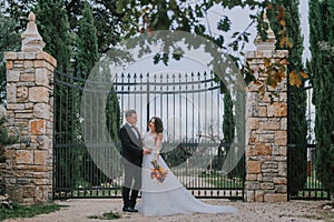 Happy stylish smiling couple walking in Tuscany, Italy on their wedding day. The bride and groom walk down the street by