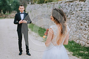 Happy stylish smiling couple walking in Tuscany, Italy on their wedding day. The bride and groom walk down the street by