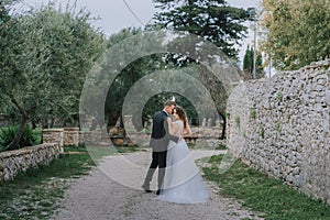 Happy stylish smiling couple walking in Tuscany, Italy on their wedding day. The bride and groom walk down the street by