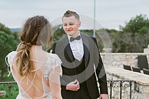 Happy stylish smiling couple walking in Tuscany, Italy on their wedding day. The bride and groom walk down the street by