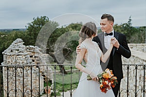 Happy stylish smiling couple walking in Tuscany, Italy on their wedding day. The bride and groom walk down the street by