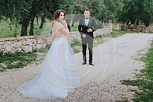 Happy stylish smiling couple walking in Tuscany, Italy on their wedding day. The bride and groom walk down the street by