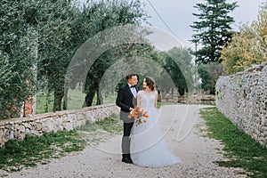 Happy stylish smiling couple walking in Tuscany, Italy on their wedding day. The bride and groom walk down the street by