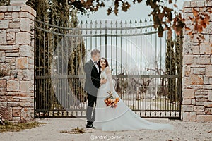 Happy stylish smiling couple walking in Tuscany, Italy on their wedding day. The bride and groom walk down the street by