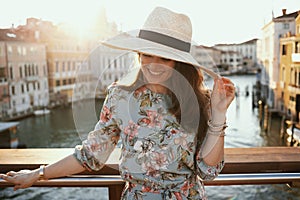 Happy stylish solo tourist woman in floral dress with hat