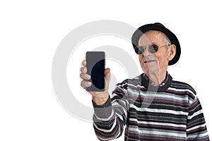 Happy stylish toothless old man in sunglasses and black hat holds phone in his hand and looking at it, isolated over
