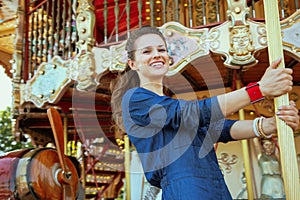 Happy stylish traveller woman riding on carousel