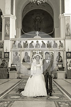 Bride and groom standing at wedding ceremony. Happy stylish wedding couple holding candles with light under golden