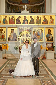 Bride and groom standing at wedding ceremony. Happy stylish wedding couple holding candles with light under golden