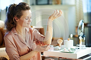 Happy stylish woman applying moisturiser on elbow photo