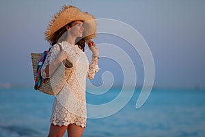 Happy stylish woman on beach at sunset relaxing