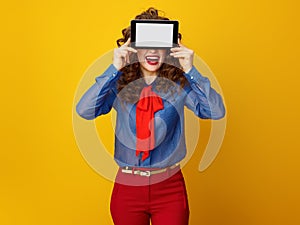Happy stylish woman hiding behind tablet PC blank screen