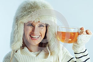 Happy stylish woman showing cup of hot tea with lemon and honey