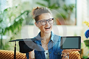 Happy stylish woman showing graduation cap and tablet PC