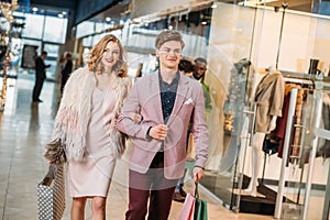 happy stylish young couple with shopping bags walking together