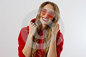 Happy stylish young woman in red hoodie, sunglasses isolated on white background. Close-up girl smiling face. Fashion and beauty