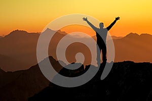 Happy success winning man on summit arms up at sunset photo