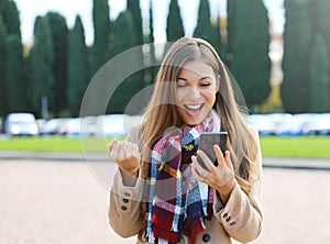 Happy success woman celebrating outdoor cheering and raising her fist up in exultation. Excited fashion woman watching her phone