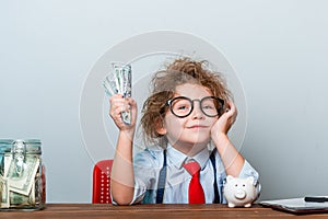 Happy successful business baby girl holding money in hand. Bunch of money. Pupil in glasses. Little businessman