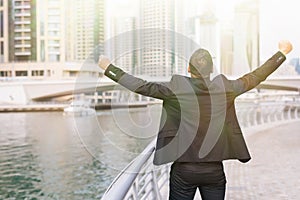 Happy successful business man celebrate win with raised arms with skyscrapers in the background