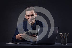 Happy Successful business man on a dark background with a money